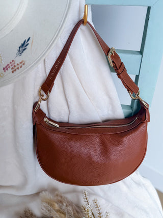 Brown leather handbag with gold accents on a white surface