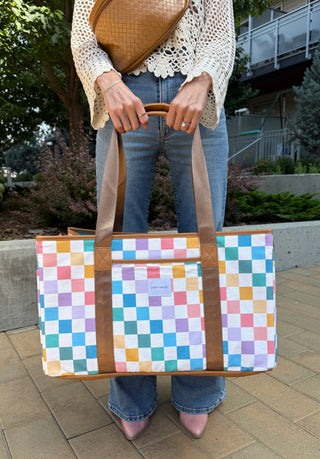 Person holding a colorful checkered bag outdoors