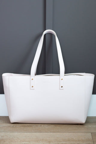 White tote bag on a wooden floor against a gray wall