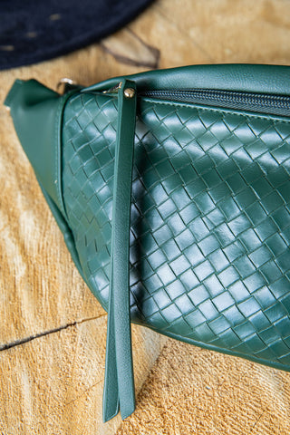 Green woven leather bag on a wooden surface