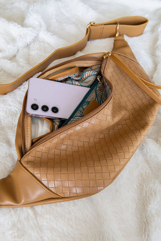 Brown woven fanny pack with phone and card on a white textured surface