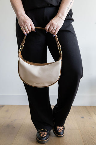 Person holding a beige handbag with a plain background
