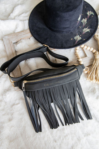 Black fringe bag with a matching hat on a textured surface