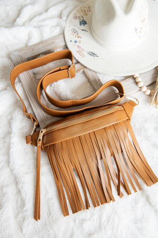 Brown leather handbag with fringe details on a white textured surface