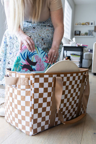 Person holding a checkered bag with a colorful item inside, in a home setting.