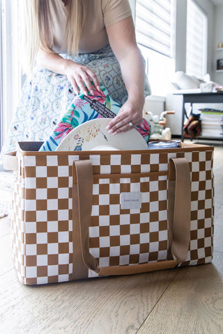 Person organizing items in a large checkered bag indoors