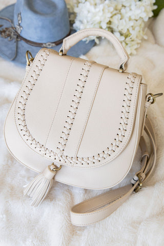 Beige handbag with decorative stitching on a soft white background