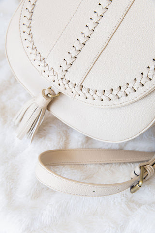 Beige handbag with braided detail and tassel on a white background