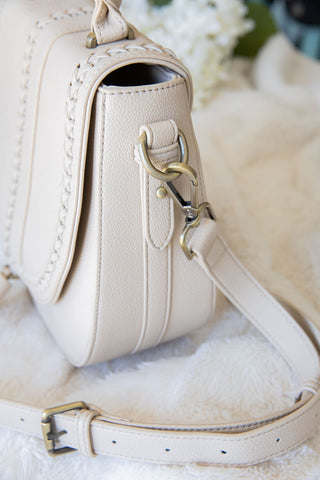Close-up of a beige handbag with a floral background