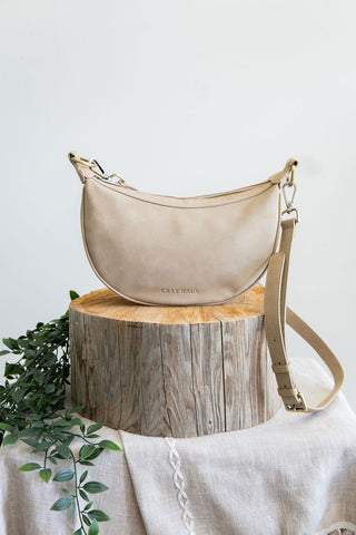 Beige handbag on a wooden stump with a white background